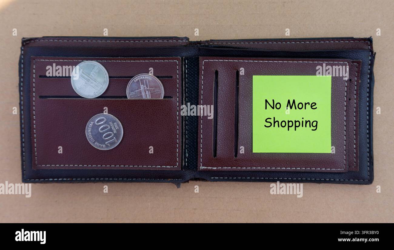 Offenes Portemonnaie mit Münzen und einem Klebezettel mit der Aufschrift "No More Shopping", das Budgetierung, finanzielle Disziplin und Geld sparen darstellt Stockfoto