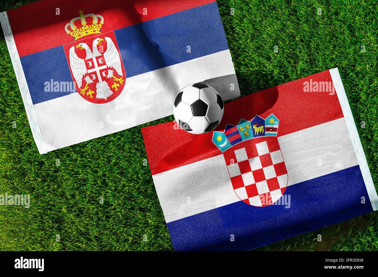 Fußballspiel Serbien gegen Kroatien. Nationalflaggen auf grünem Rasen mit einem Fußball in der Mitte. Fußballhintergrund für ein internationales Spiel. Stockfoto