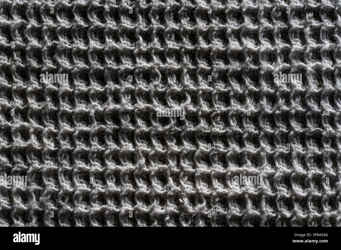 Stofftextur mit Waffelgewebe, graues Baumwollmaterial-Hintergrund. Oberansicht der grauen Waffelhandtuchtextur. Vollflächiger Hintergrund aus Zellstoff-Baumwolle oder -Leinen Stockfoto