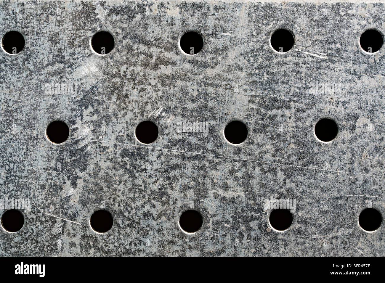 Perforierte galvanisierte Metallplattentextur mit Löchern. Industrielle perforierte Stahlplatte. Hintergrund aus zinkbeschichteter Eisengitterplatte mit kreisförmigen Löchern Stockfoto