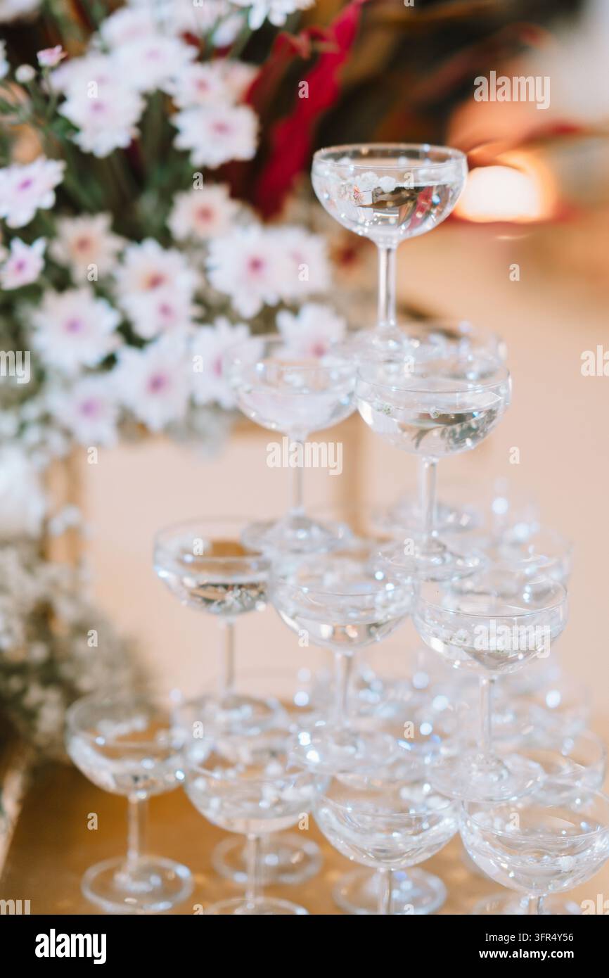 Elegante Champagnerglas-Pyramide mit weißer Blumen Dekoration für eine Hochzeitsfeier Stockfoto