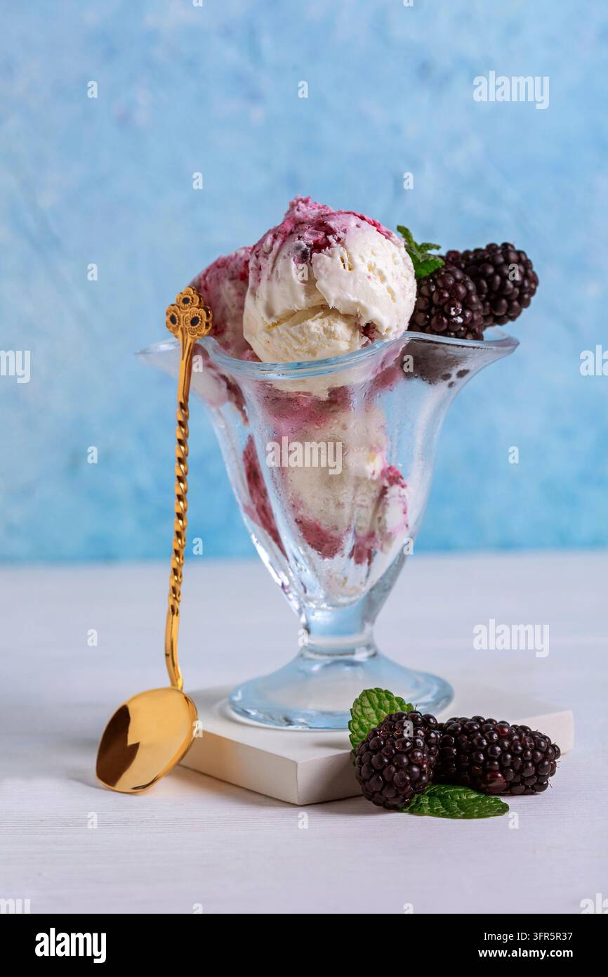 Glaserne Schale mit cremigem Beeren-Eis wird mit frischen Brombeeren serviert, selektiver Fokus. Sommerdessert Stockfoto