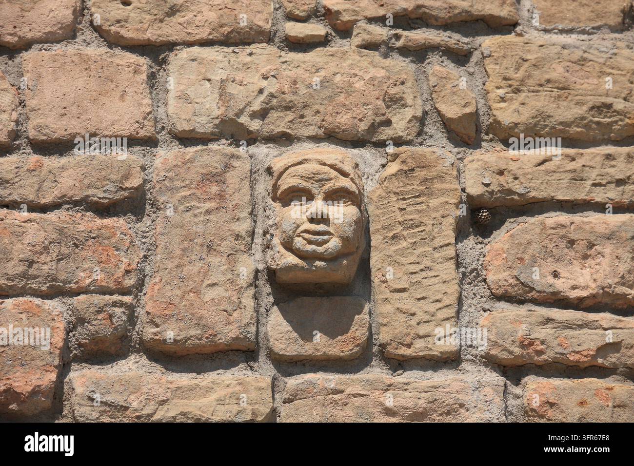 Steinporträt an einer Wand - sonnenbeschienen Stockfoto