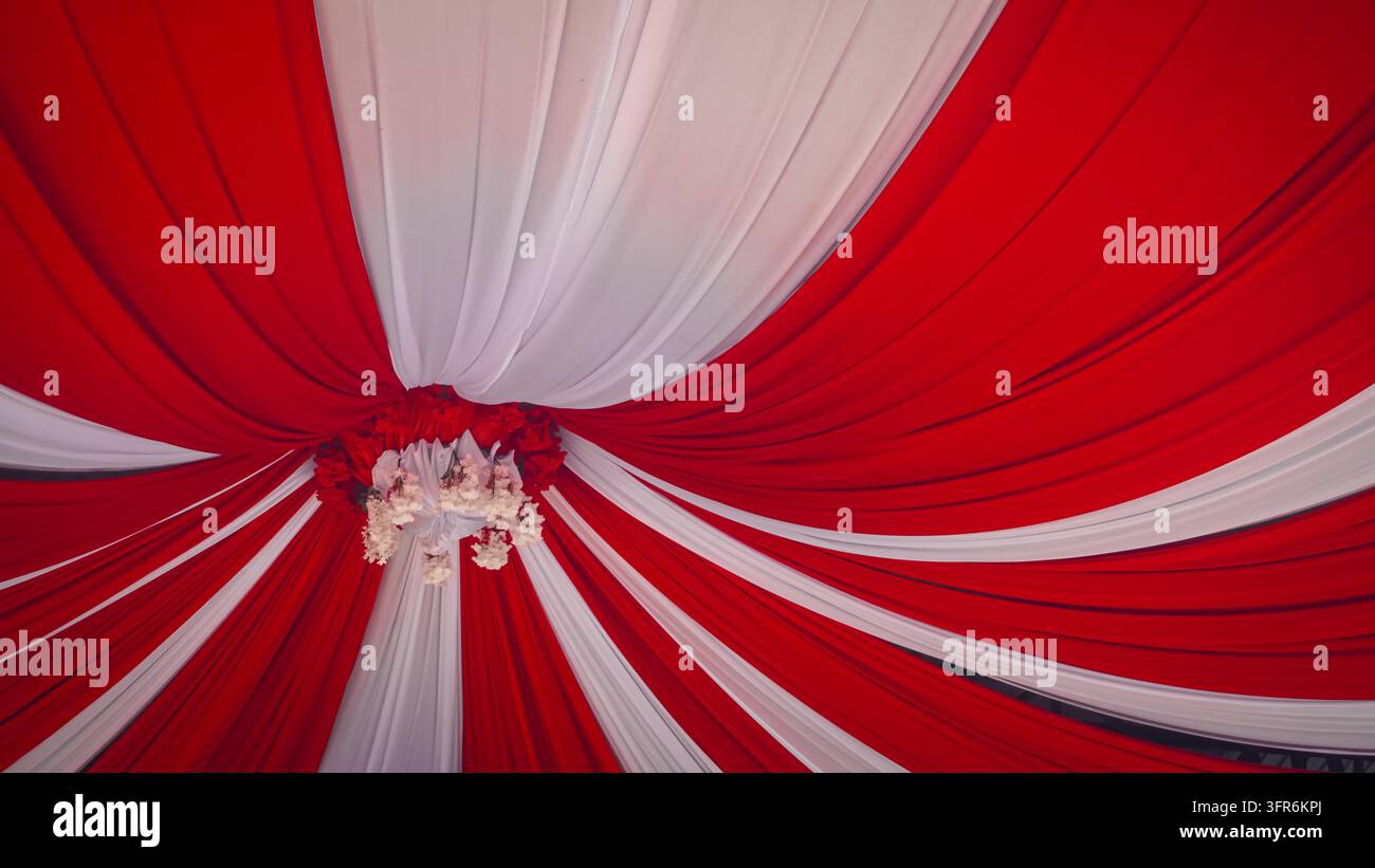 eine rote und weiße plissierte Stoff-Zeltdekoration, allgemein als Plafon Tenda, Terop oder Layos bezeichnet, die für festliche Veranstaltungen, Hochzeiten und Stockfoto