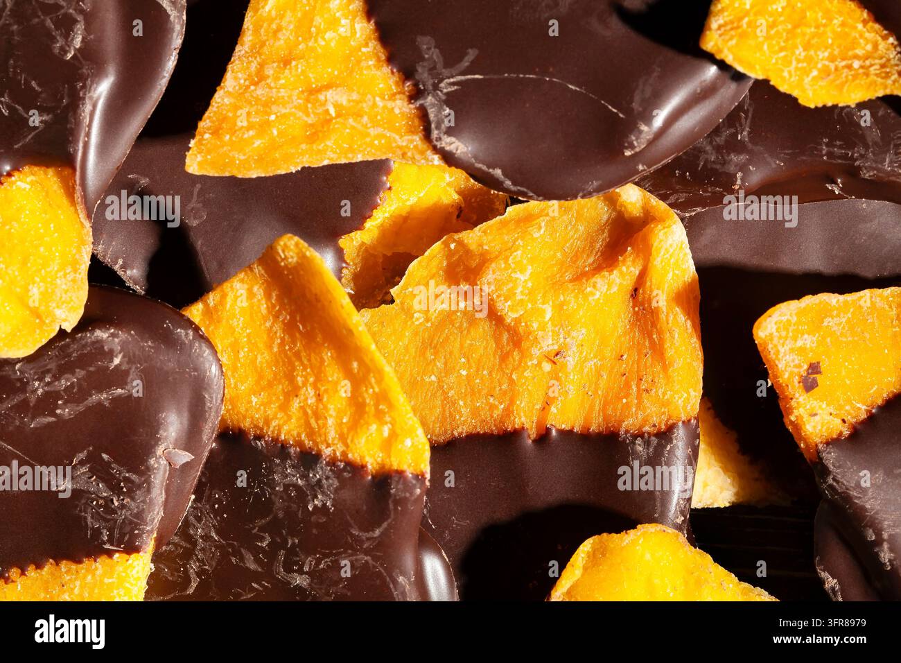 Schokoladengetaufter Mango auf schwarzem Hintergrund, Ansicht von oben Stockfoto