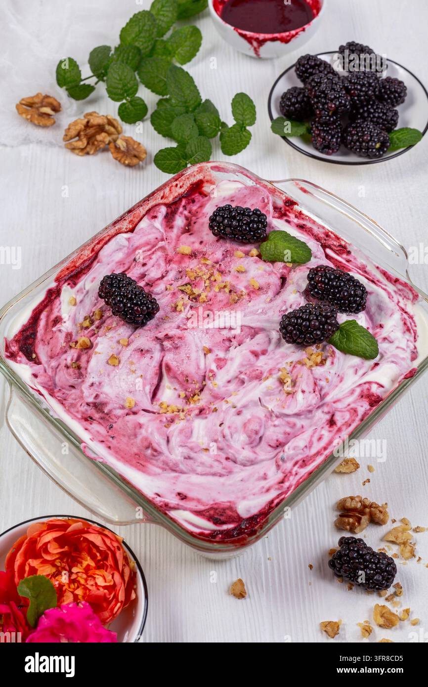 Hausgemachtes Brombeereis in einem Glasbehälter mit Brombeeren und Minzzweigen Stockfoto