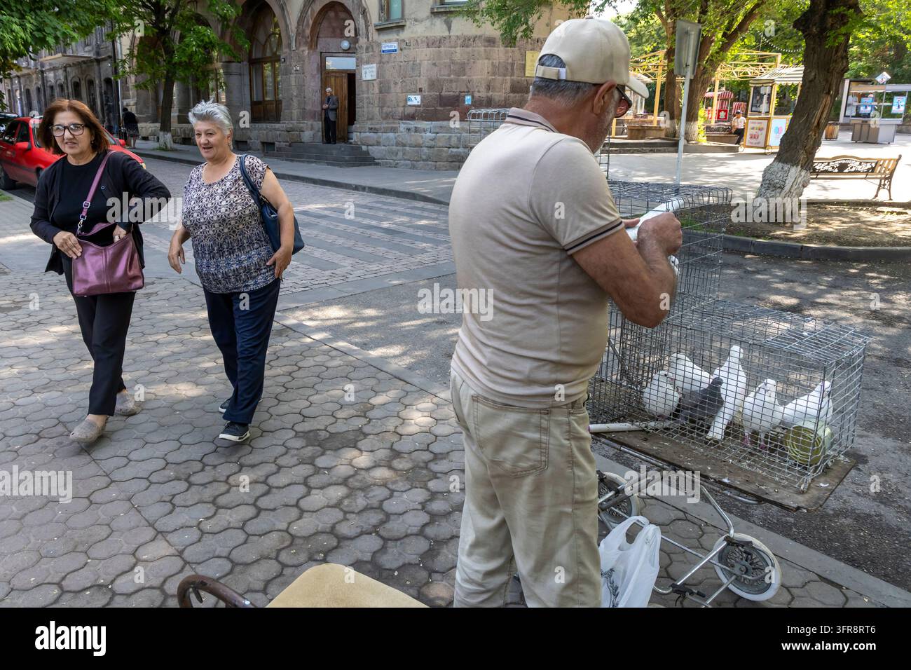 Mann hält einen weißen Tauber, der aus einem Käfig auf einer Stadtstraße genommen wurde, Provinz Shirak, Gjumri, Armenien Stockfoto