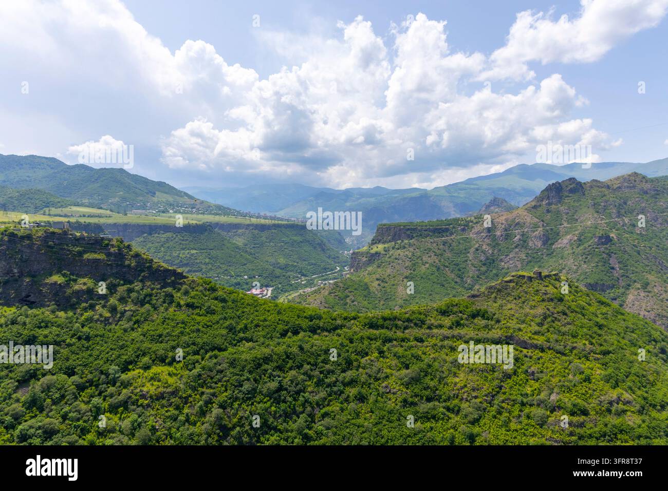 Luftbild eines tiefgrünen Canyons mit Klippen und entfernten Klosterruinen auf einem Hügel, Lori-Provinz, Haghpat, Armenien Stockfoto