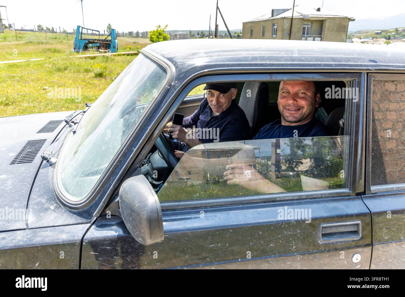Zwei Männer sitzen in einem alten Auto in einem ländlichen Dorf, Gegharkunik-Provinz, Noratus, Armenien Stockfoto