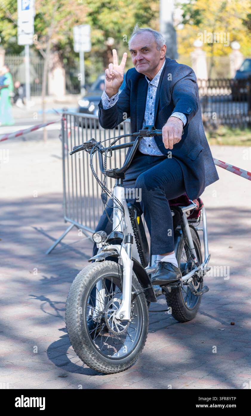 Reifer Mann auf einem Elektrofahrrad macht ein Friedenszeichen Stockfoto