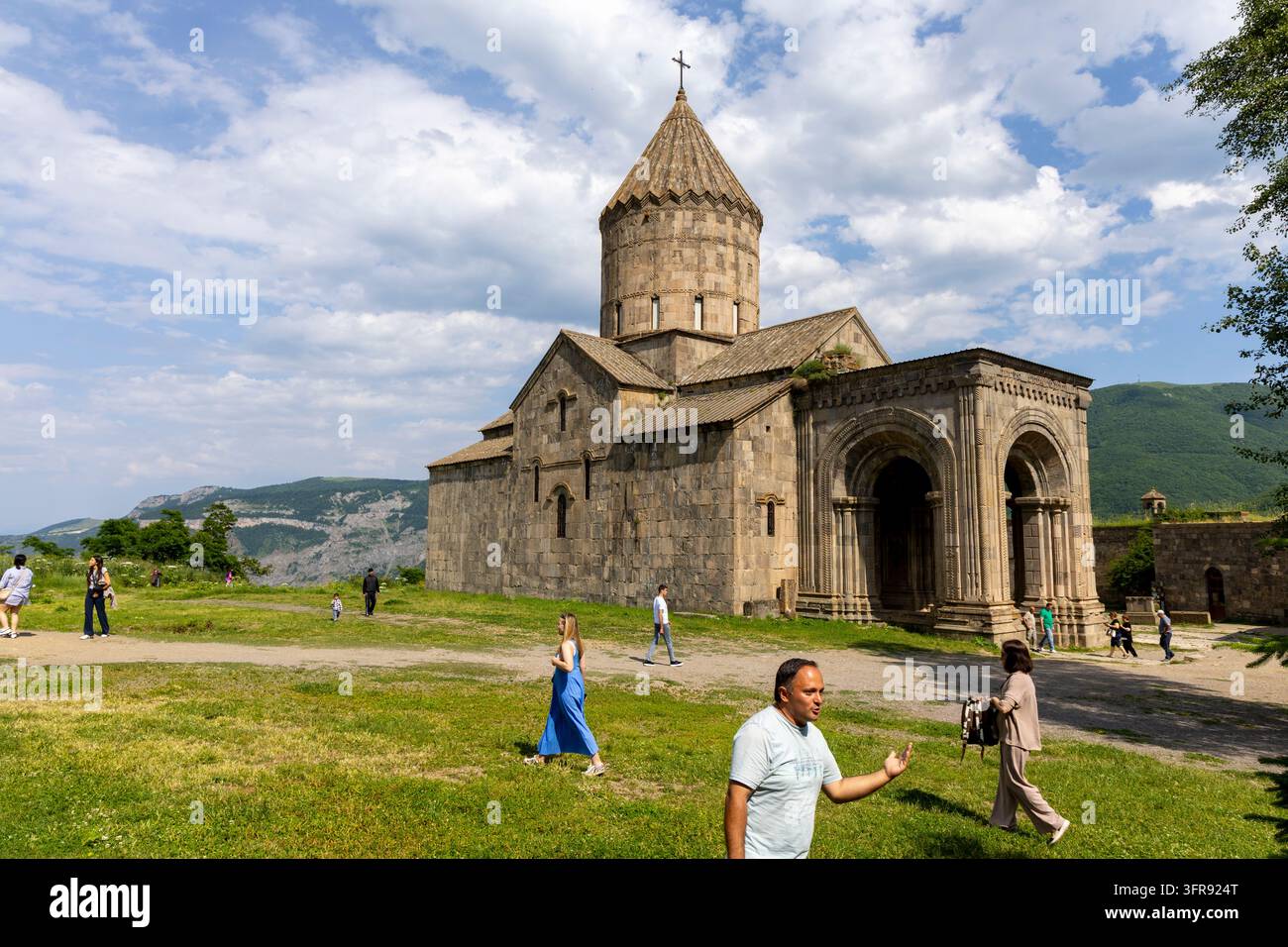 Fassade der Tatev-Klosterkirche mit vielen Touristen, die über das Gras davor gehen, Syunik-Provinz, Tatev, Armenien Stockfoto