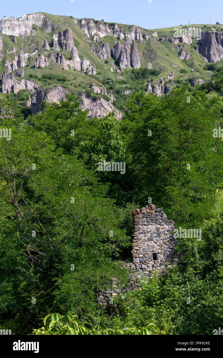 Verfallenes Steingebäude zwischen Bäumen unter den Höhlenwohnungen des Troglodyten-Dorfes, Provinz Syunik, Khndzoresk, Armenien Stockfoto