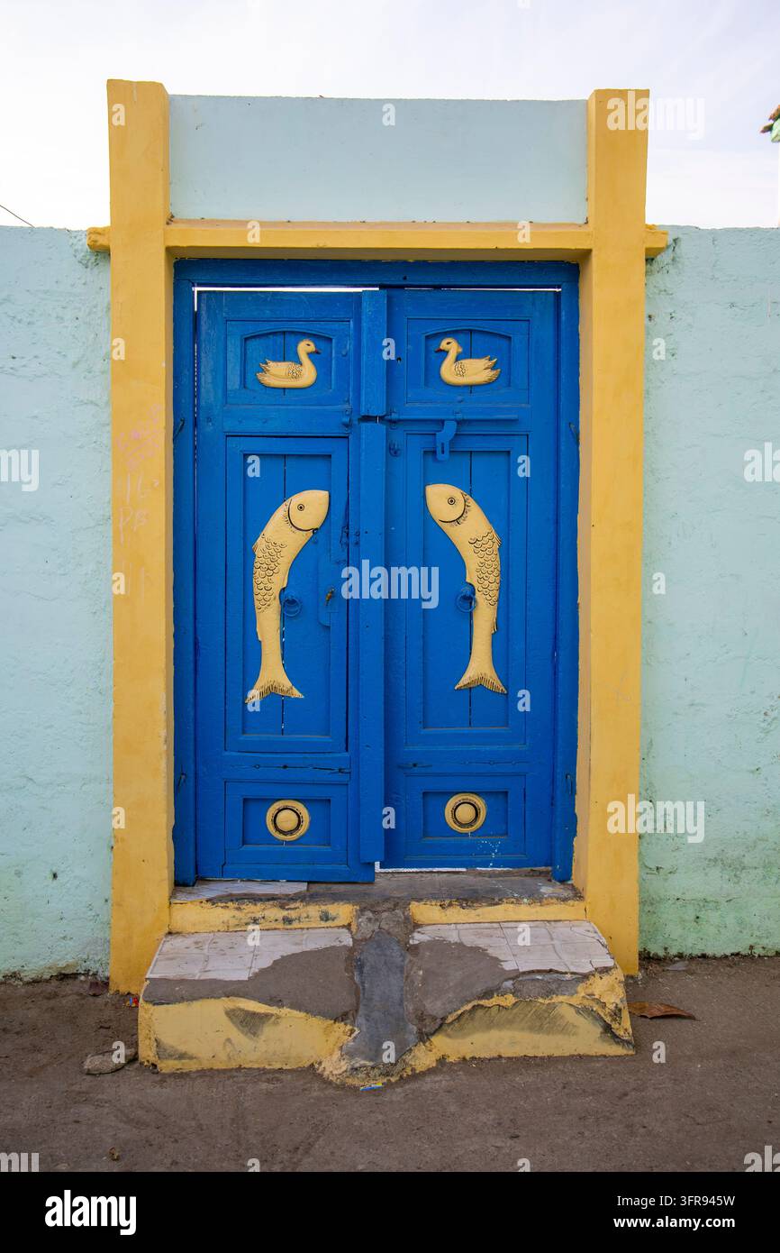Blaue hölzerne Doppeltür mit geschnitzten gelben Fisch- und Entenmotiven an einem Hauseingang, Gujarat, Mandvi, Indien Stockfoto