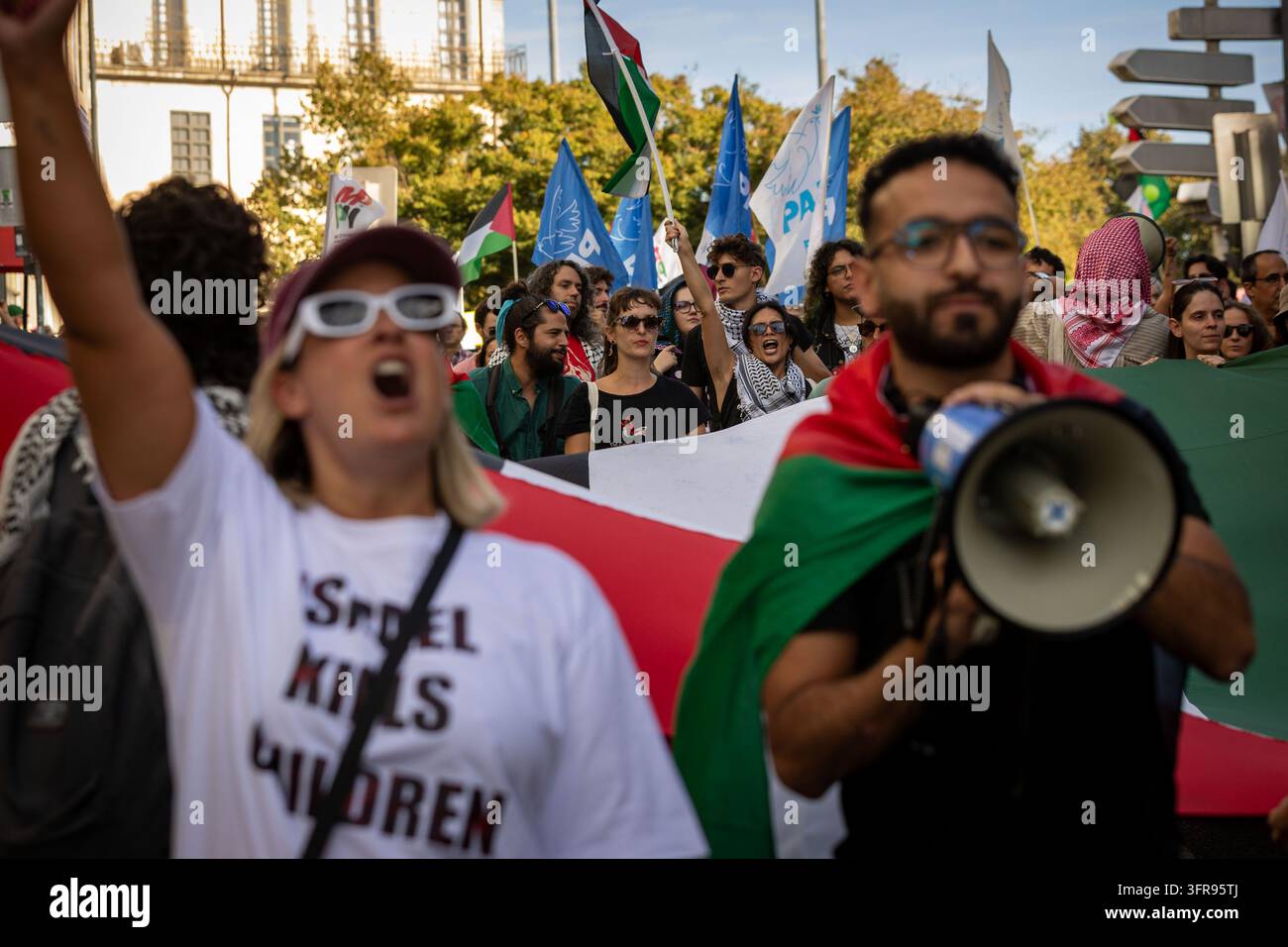 Demonstranten, die palästinensische Flaggen tragen, skandieren Parolen zu Beginn eines Marsches in Solidarität mit Palästina, nachdem sie sich auf der Praça dos Poveiros in Porto versammelt haben. Stockfoto