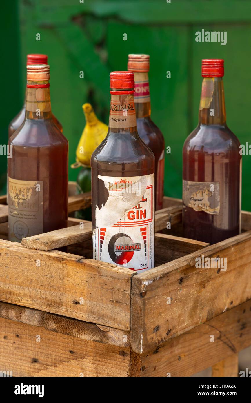 Alte Glasflaschen mit Gin stehen zusammen in einer Holzkiste vor einer grünen Wand, Maritime Region, Lome, Togo Stockfoto
