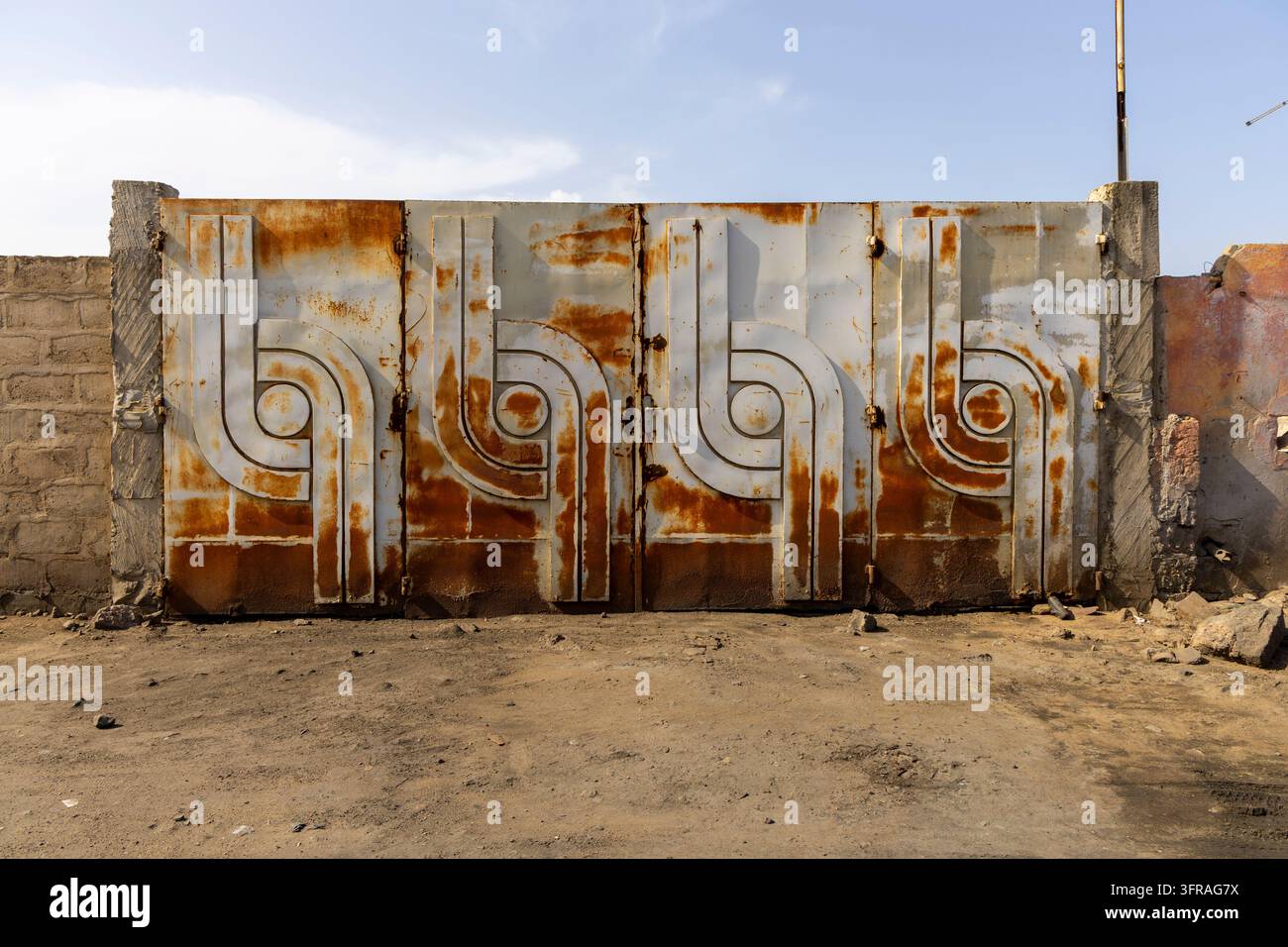 Rostiges dekoratives Eisentor mit einem wirbelnden Muster an einer Betonwand, Maritime Region, Lome, Togo Stockfoto