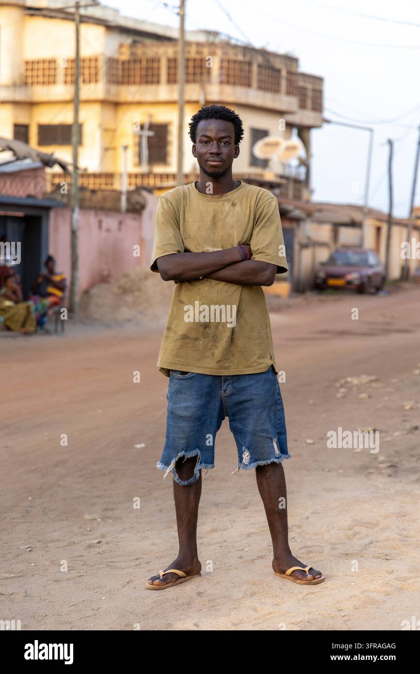 Porträt eines jungen Mannes, der mit verschränkten Armen auf einer Straße steht, Maritime Region, Lome, Togo Stockfoto
