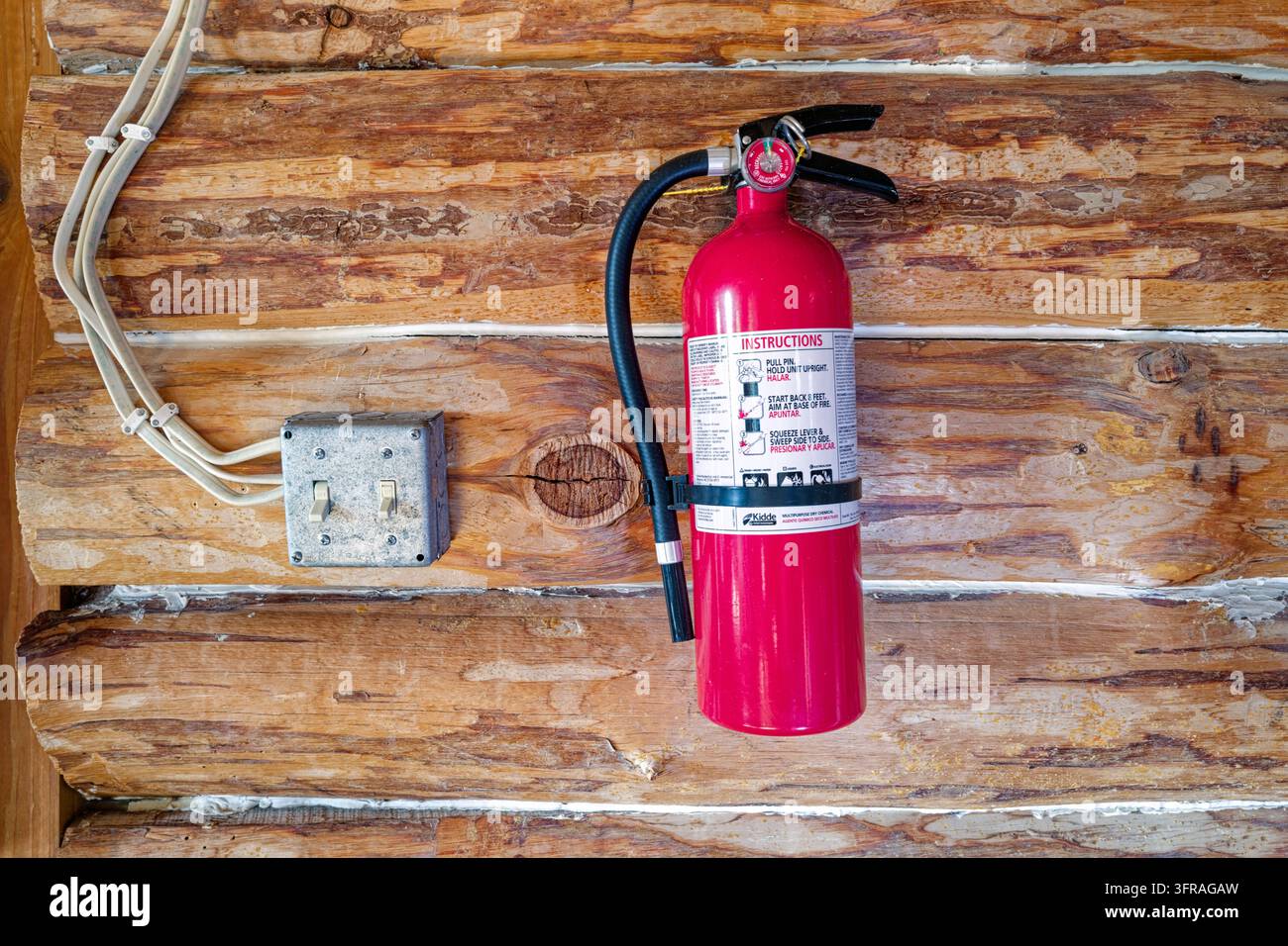 Lichtschalter und ein Feuerlöscher an der Innenwand einer rustikalen Blockhütte Stockfoto