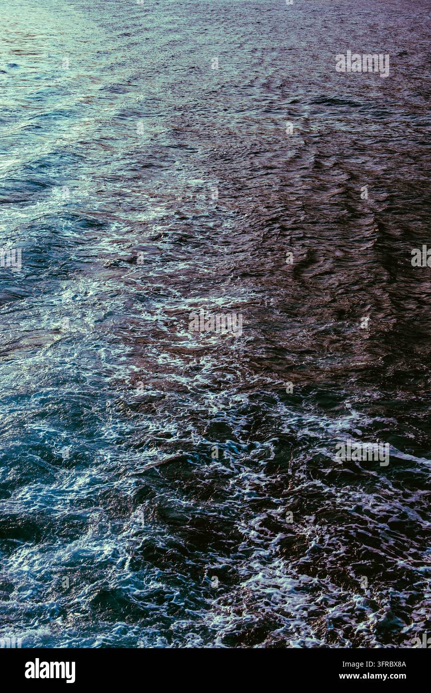 Nahaufnahme von blauem Ozeanwasser mit komplexen Wellen, fließenden Strömungen und schimmernden Reflexionen in Türkis- und Tiefvioletttönen. Ein dynamisches Aquati Stockfoto