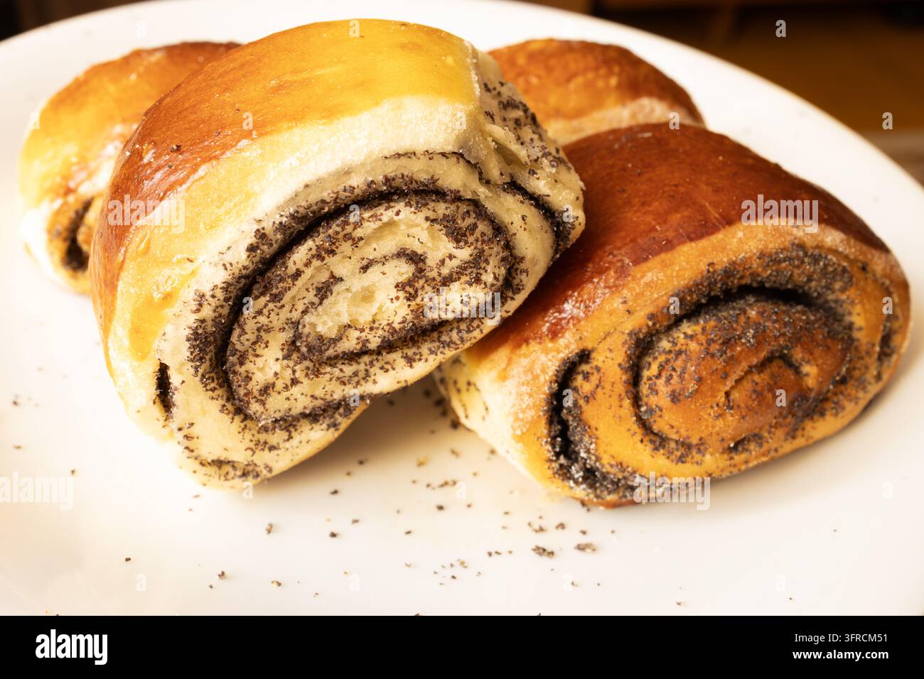 Süße Mohnrollen mit Spiralfüllung auf weißem Teller, Nahaufnahme Stockfoto