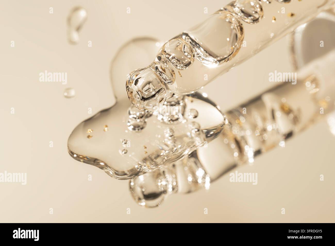 Pipette mit fallendem Tropfen 24-karätigen Goldöls. Tropfengefäß mit Lotion, Essenz, Serum, Emulsion. Natürliches organisches Kosmetikum. Körperpflegekonzept Stockfoto