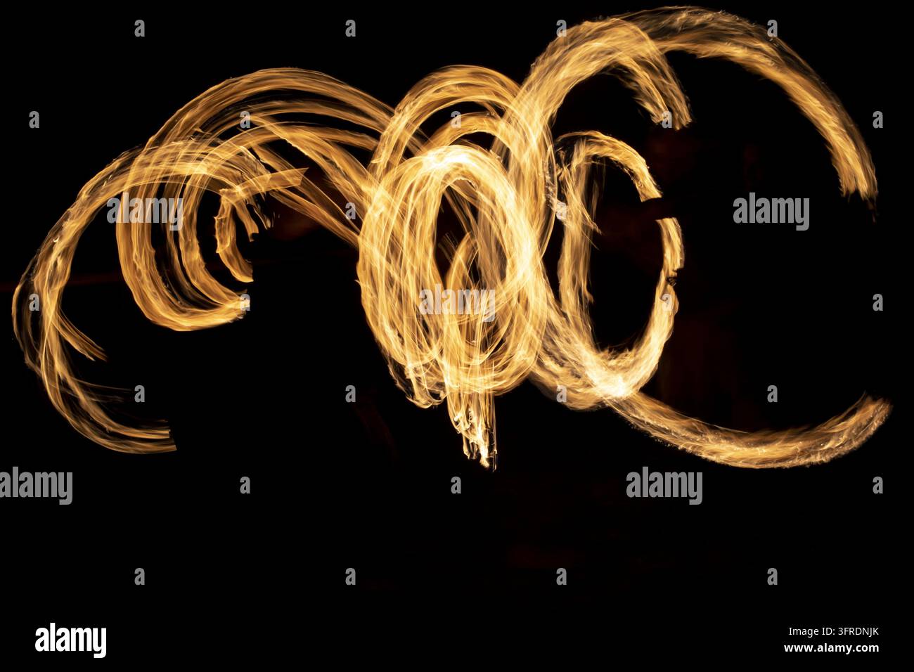 Kreise aus Flammen im Dunkeln. Feuershow bei langer Belichtungszeit. Flammen. Feuer auf schwarzem Hintergrund Stockfoto