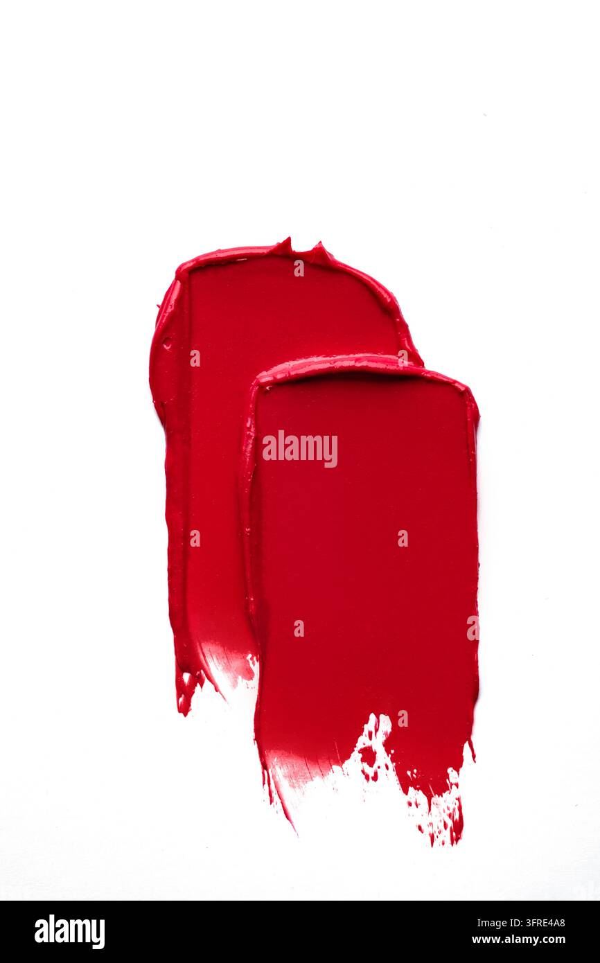 Dicke Pinselstriche eines roten Kosmetikprodukts mit feinen Glitzerpartikeln. Dieser elegante Farbklecks zeigt eine luxuriöse Textur und Farbe, geeignet für Ups Stockfoto