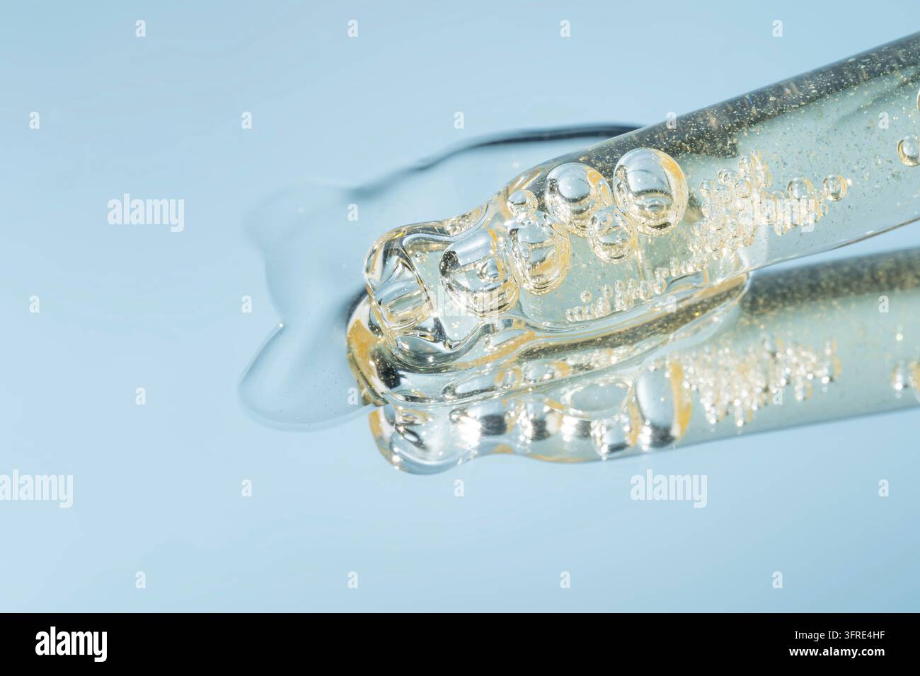 Tropfen von Kosmetikserum und eine Pipette. Ein Hautpflegeprodukt. Blauer Hintergrund. Kopierplatz Stockfoto