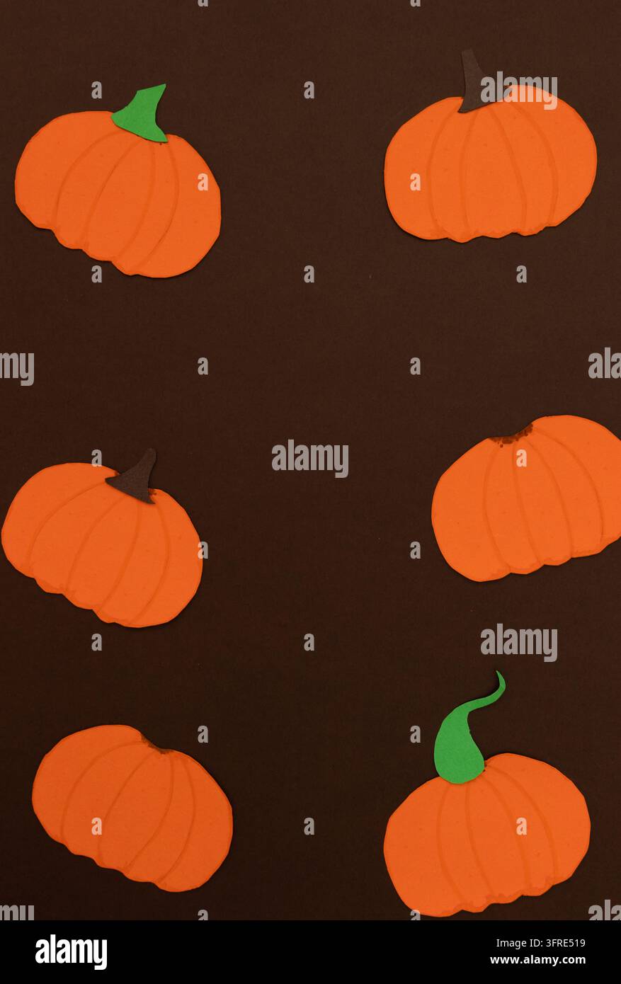 Papierkürbisse mit dekorativen Designs auf einem dunkelbraunen Hintergrund, mit Platz für Text, visueller Ressource für Werbung, Grafikdesign und Herbst Stockfoto