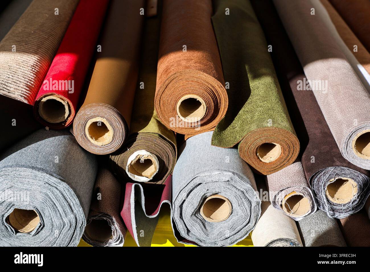 Rollen farbenfroher Stoffe, die eine Auswahl an Texturen und Materialien für Näharbeiten, Polsterarbeiten und Bastelprojekte präsentieren Stockfoto
