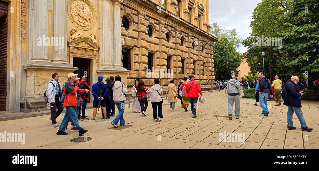 Besucher passieren den Eingang und die lange rustizierte Fassade des Palastes von Karl V. Stockfoto