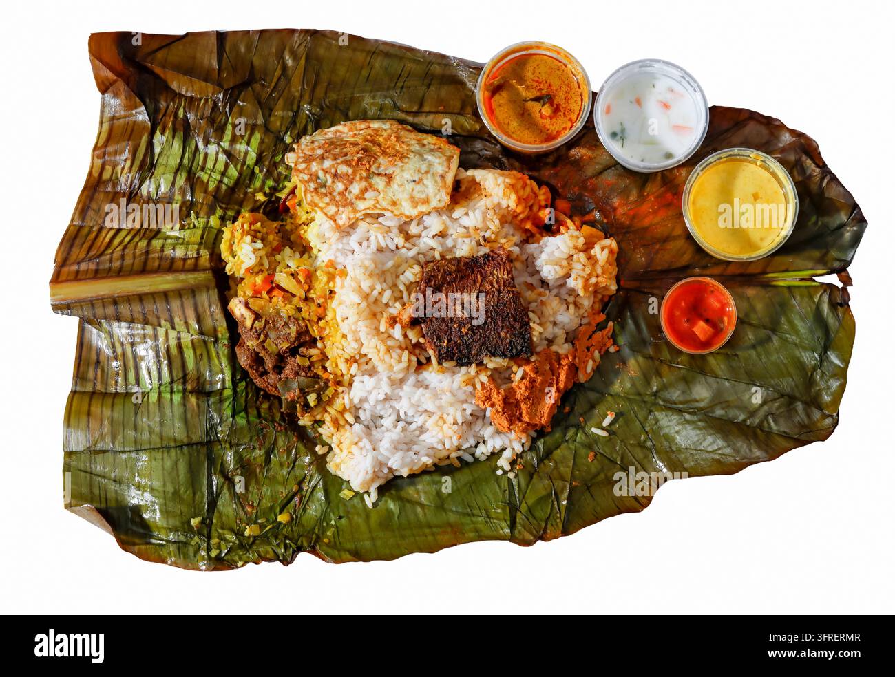 Traditionelles südindisches Pothi Choru Reisparcel, geöffnet auf Bananenblatt mit gebratenem Fisch, Omelett, Currys und Pickle. Stockfoto