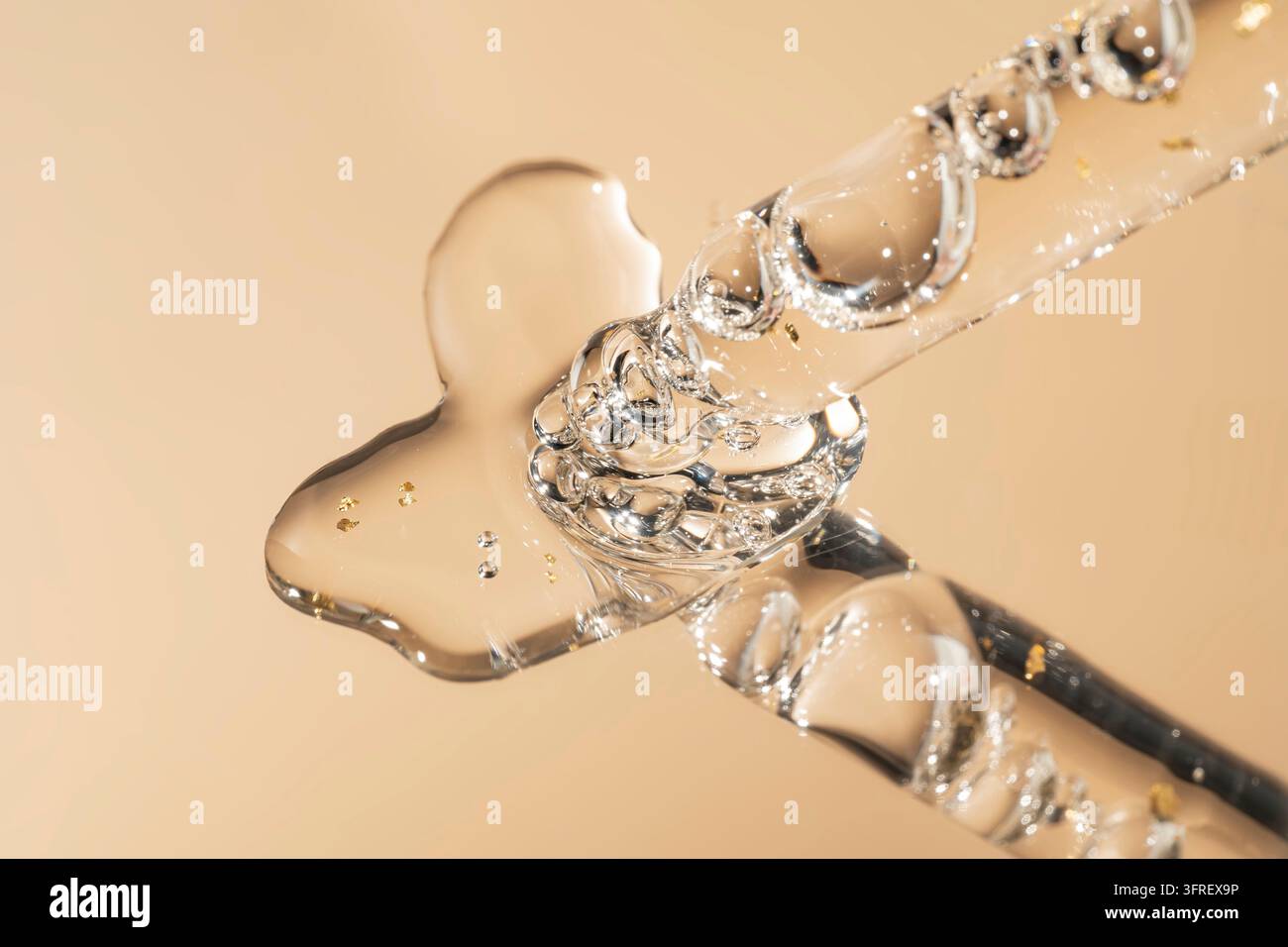 Pipette mit fallendem Tropfen 24-karätigen Goldöls. Tropfengefäß mit Lotion, Essenz, Serum, Emulsion. Natürliches organisches Kosmetikum. Körperpflegekonzept Stockfoto