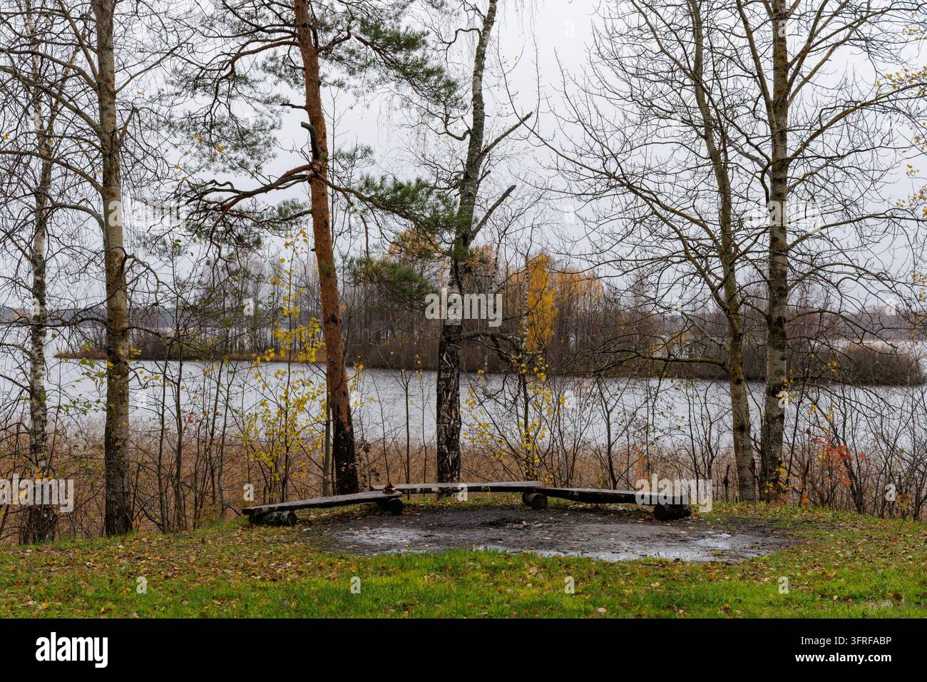 Pittoreske horizontale Landschaft eines leeren Picknickplatzes an ruhigem Wasser unter bewölktem Himmel in Nordeuropa. Stockfoto