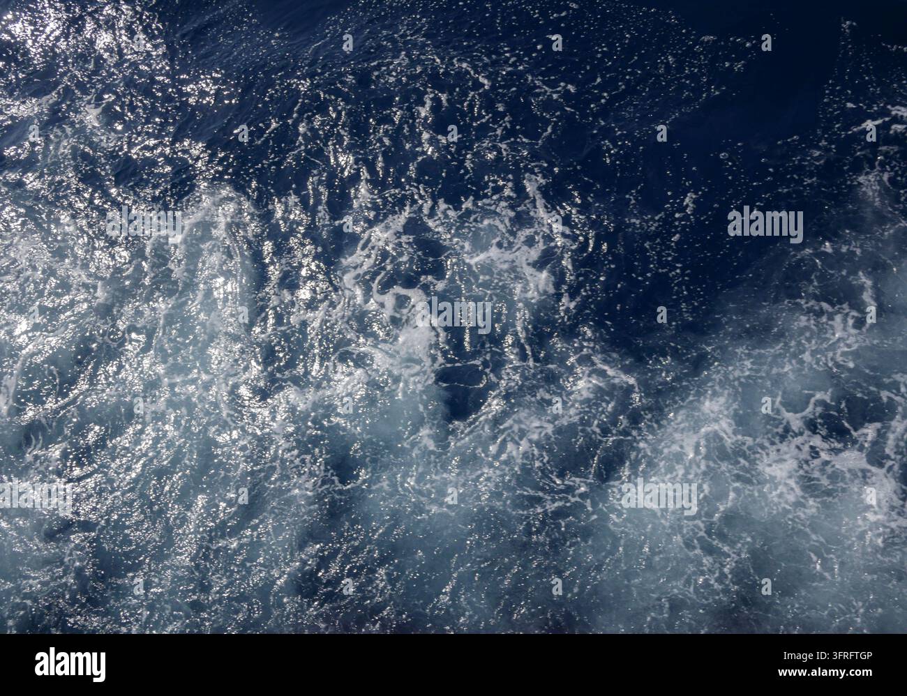 Ozeanwellen-Schaum auf tiefblauem Wasser als Texturrückgrund Stockfoto