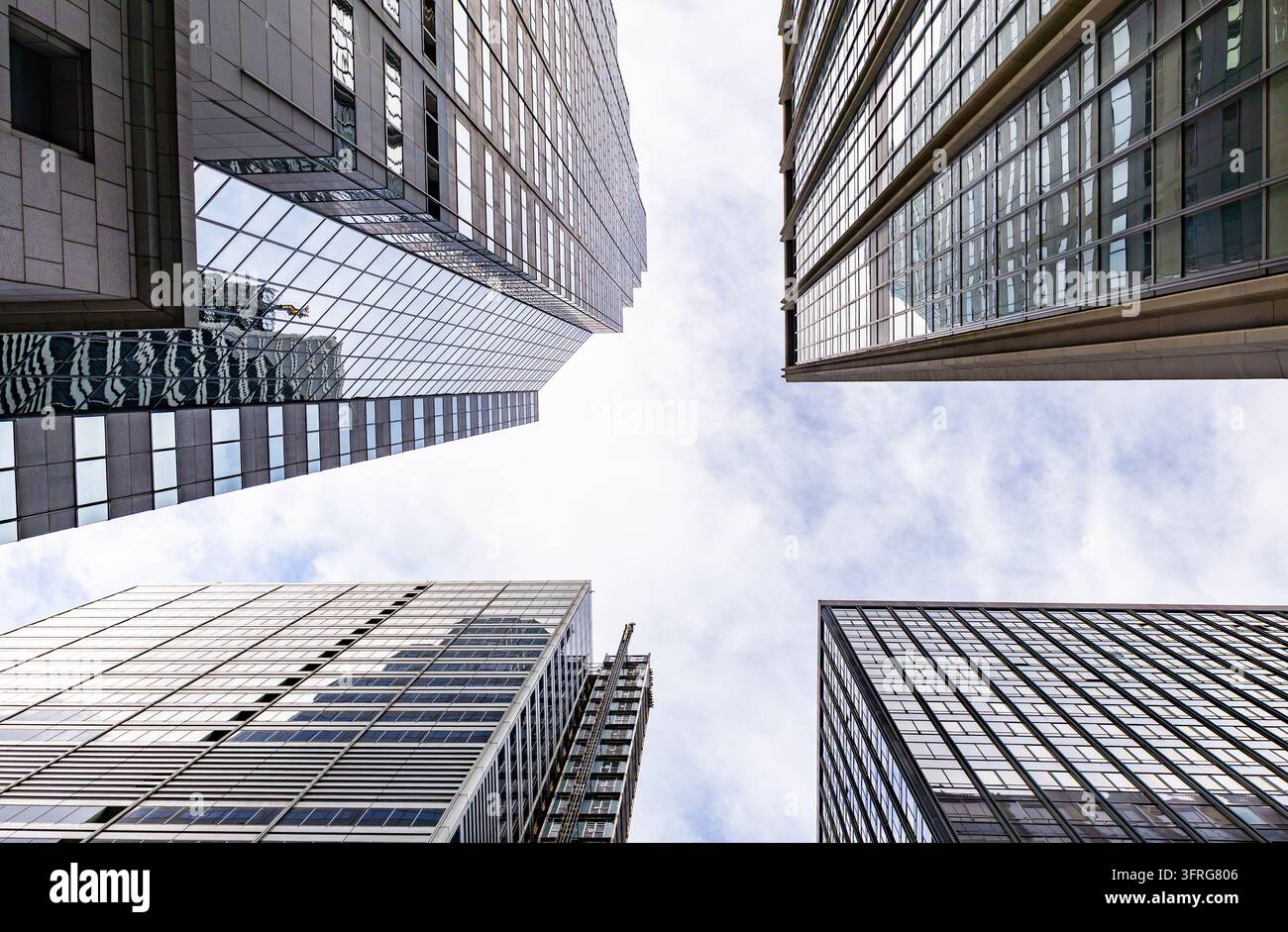 Symmetrische Niedrigwinkelperspektive der minimalistischen Dachgeometrie von Wolkenkratzern vor einem blassen Himmel Stockfoto
