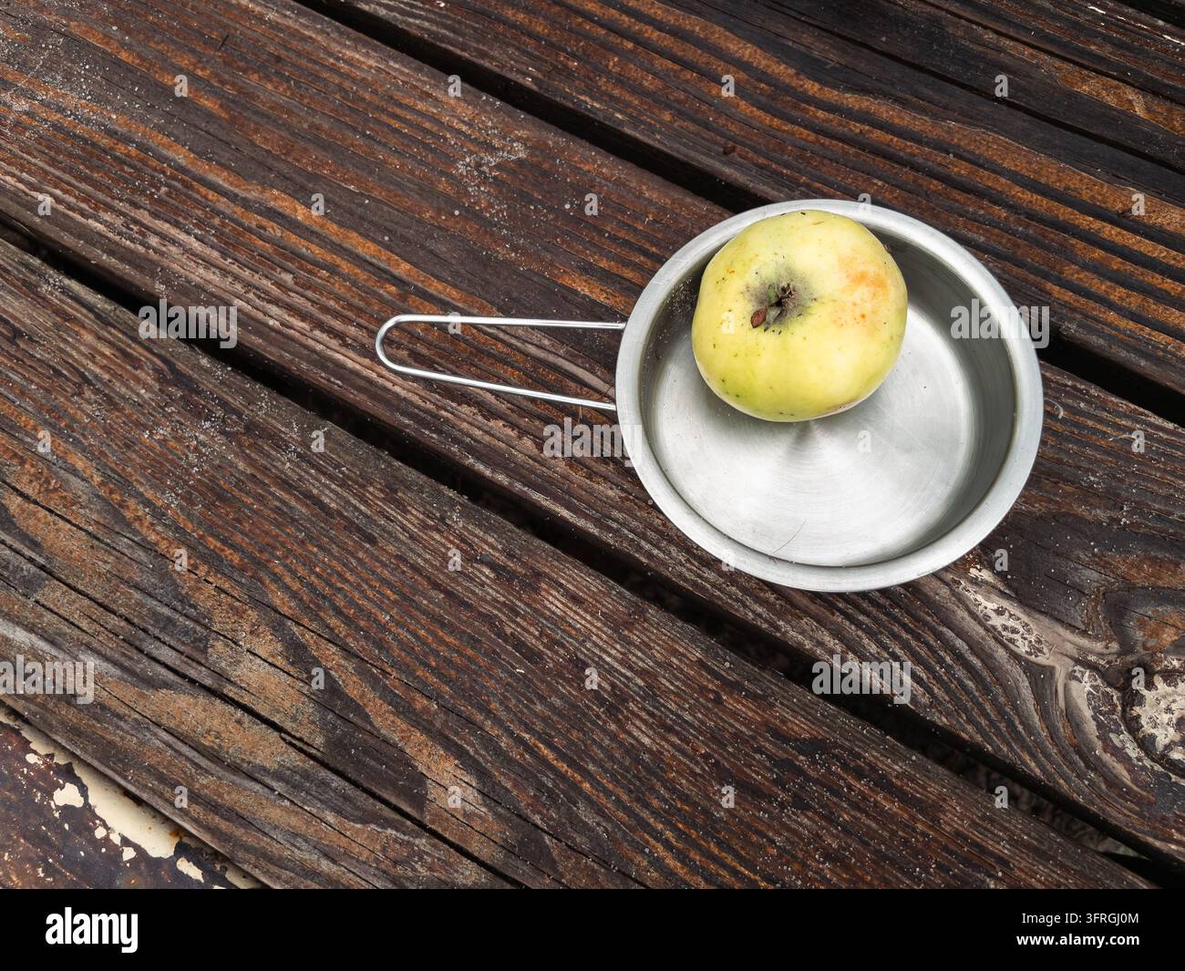 Frischer grüner Apfel in einer Edelstahlschale auf einem rustikalen Holztisch - Smartphone-aufgenommenes Stockfoto