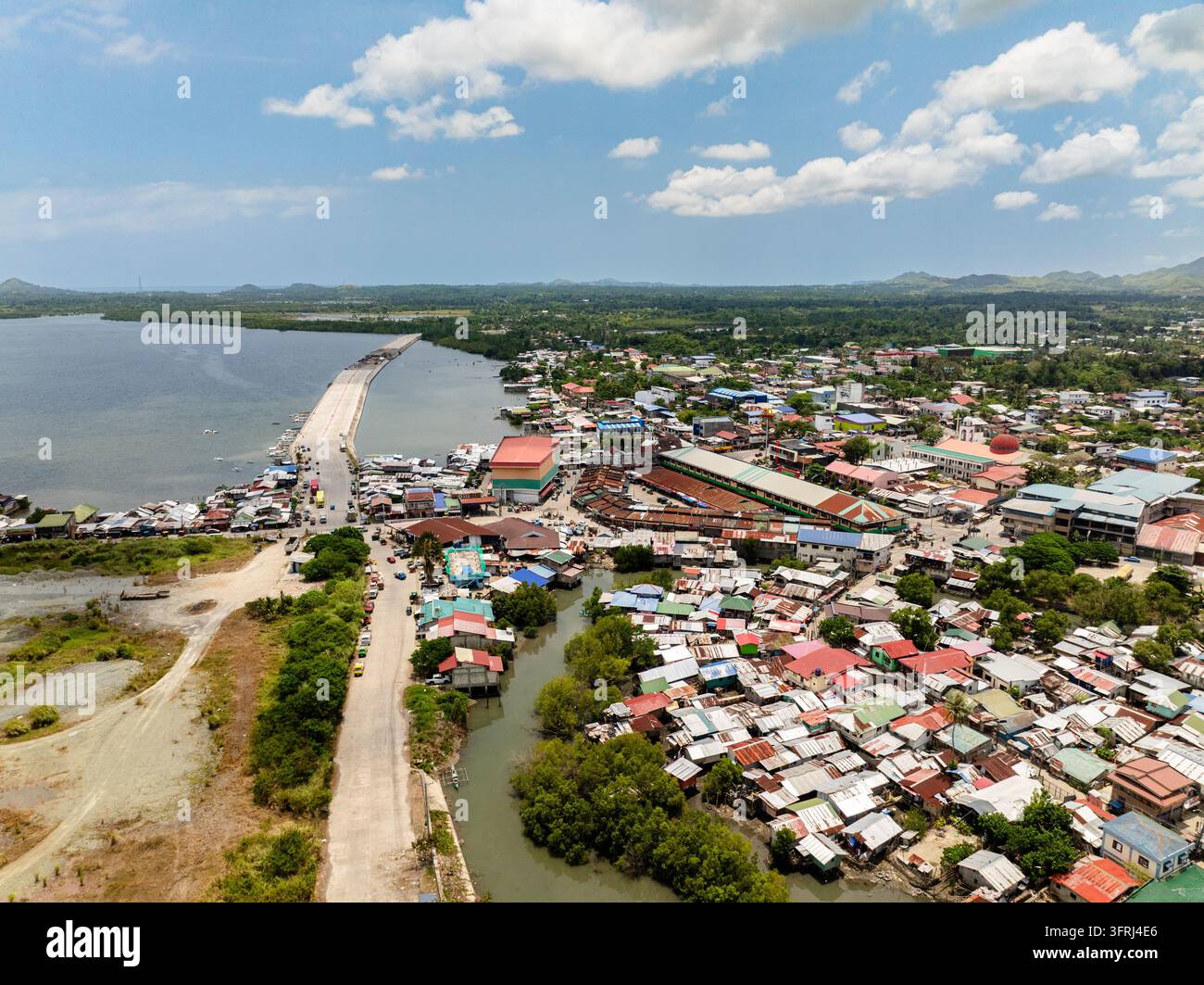 Küstenstadt mit dichter Bebauung, einer langen Dammstraße, die ins Meer reicht. Ubay, Bohol, Philippinen Stockfoto