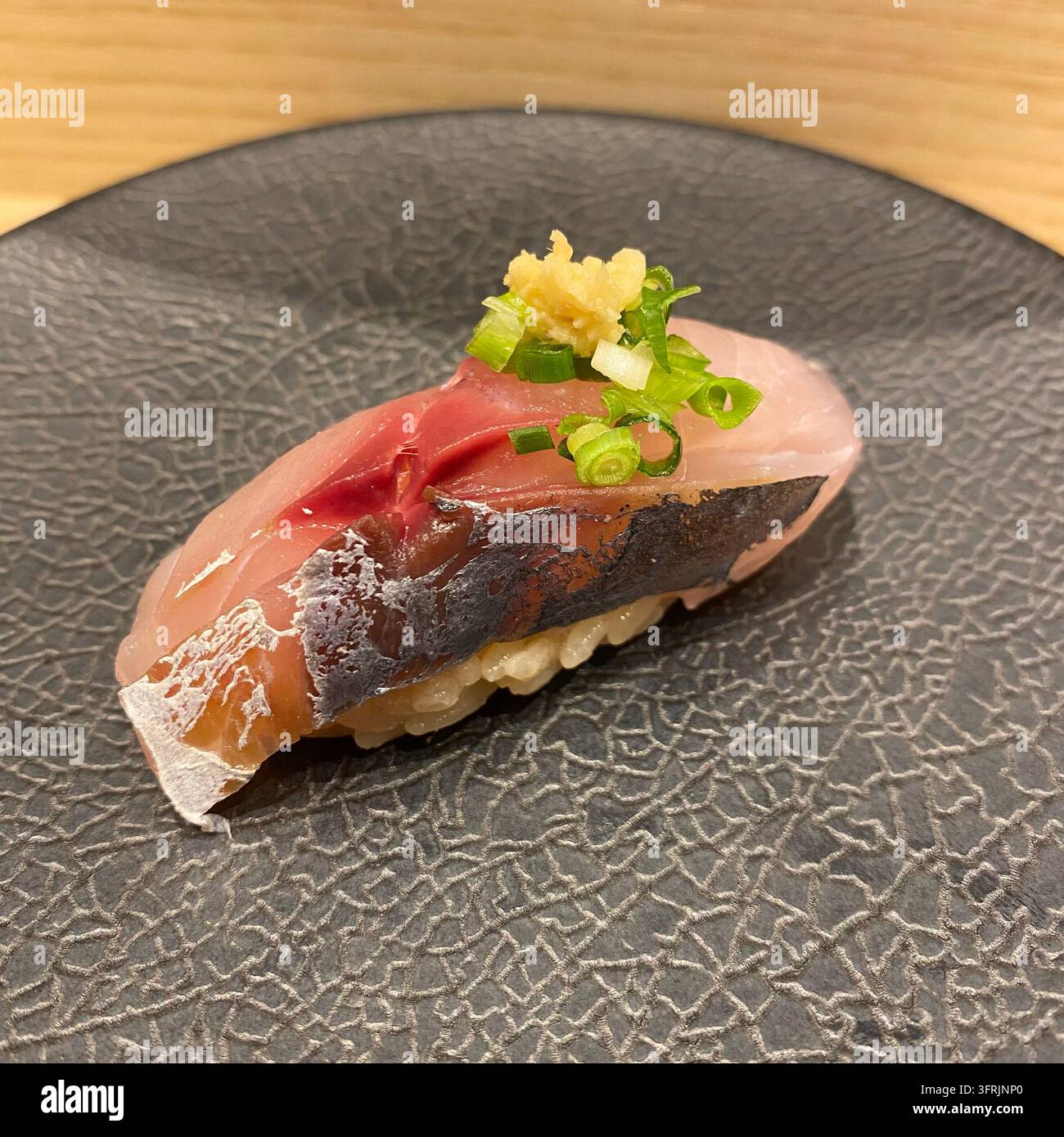 Horsemackerel Nigiri Sushi mit gehackter Frühlingszwiebel und geriebenem Ingwer in einem Sushi-Restaurant in Hakata, Fukuoka, Japan. Stockfoto