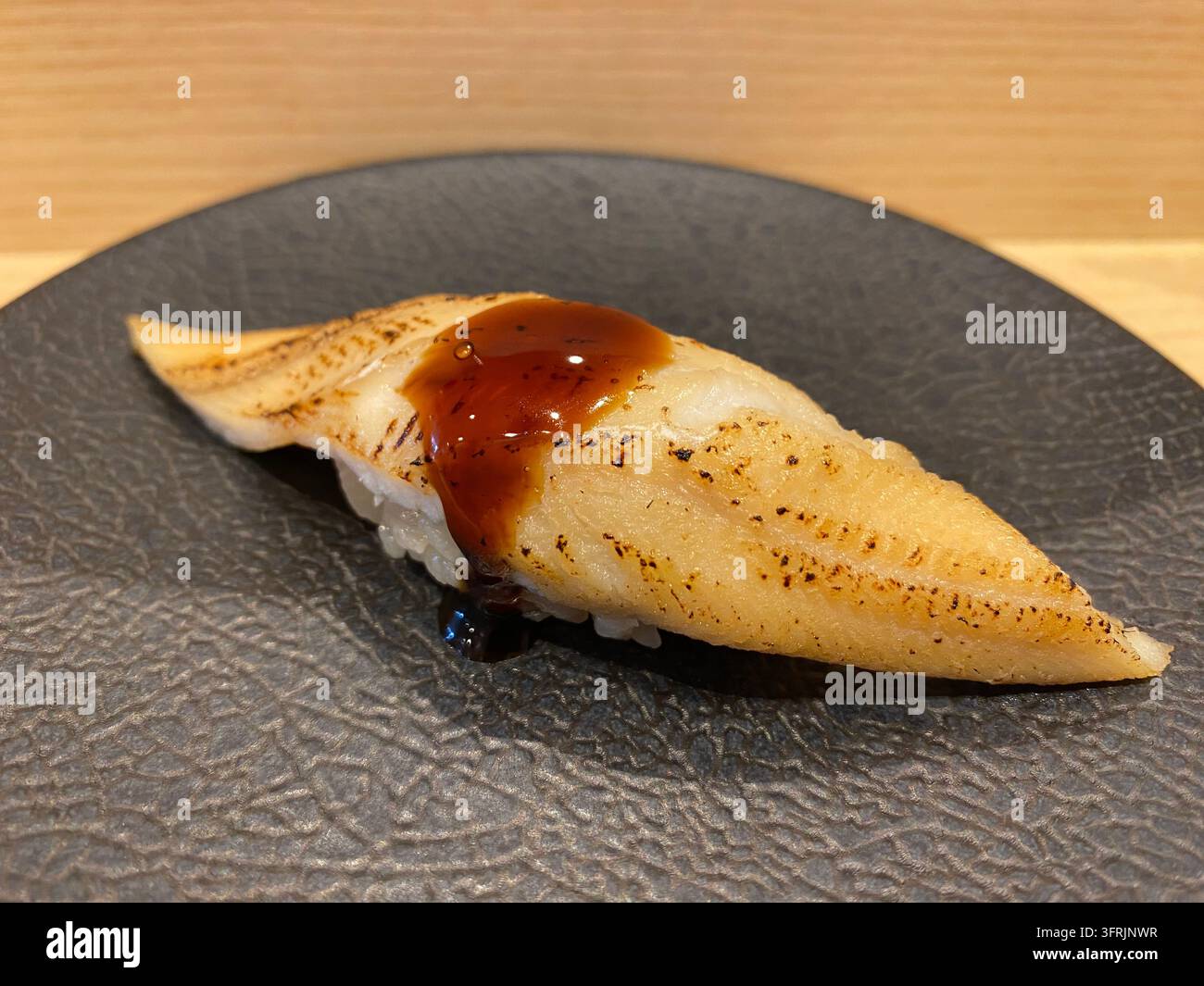 Nahaufnahme von gekochtem Muränenfisch (Anago) Nigiri-Sushi, serviert in einem Sushi-Restaurant in Fukuoka, Japan. - Smartphone-aufgenommenes Stockfoto