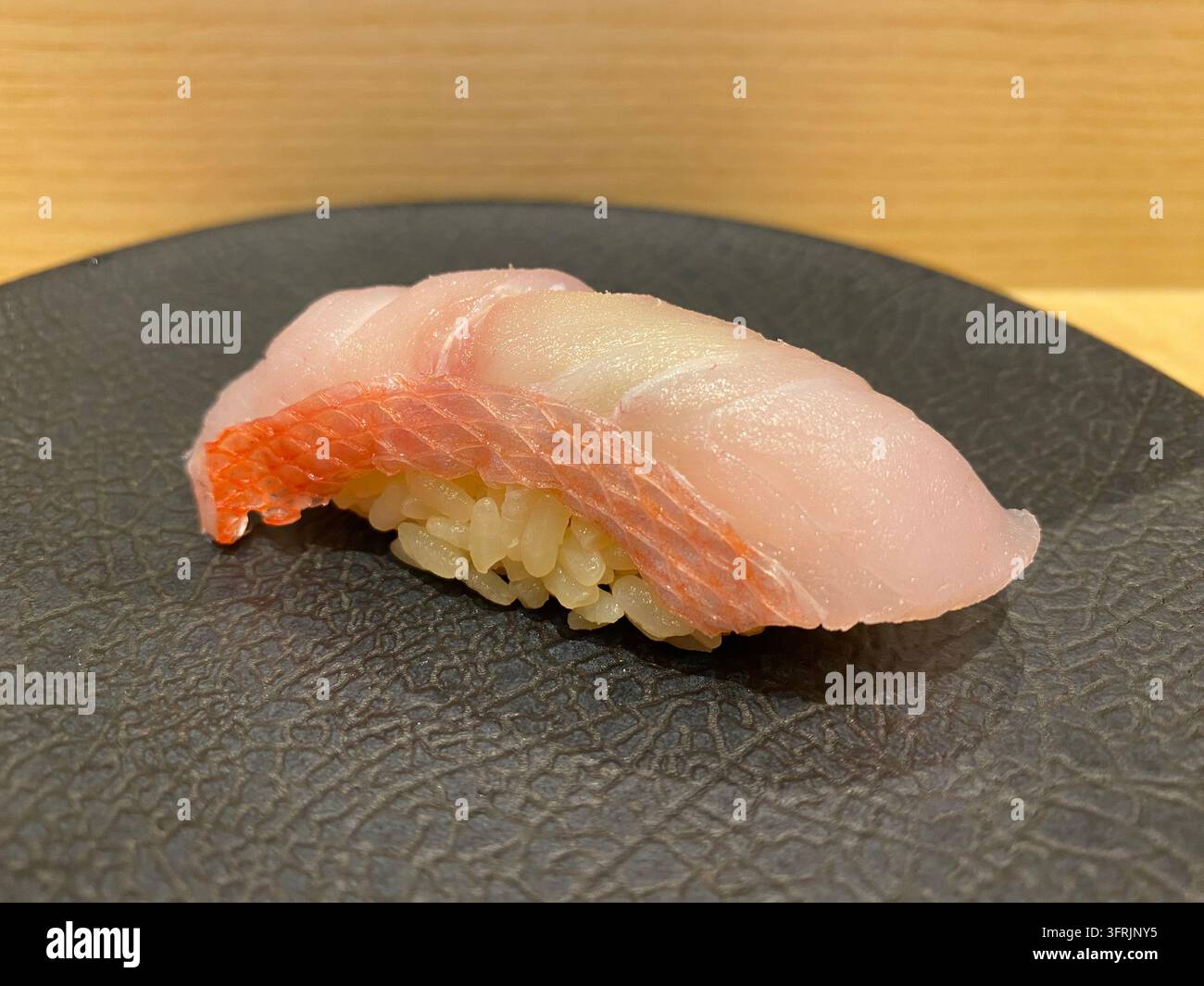Nahaufnahme von prächtigem Alfonsino (Kinmedai) Nigiri-Sushi, serviert in einem Sushi-Restaurant in Fukuoka, Japan. - Smartphone-aufgenommenes Stockfoto