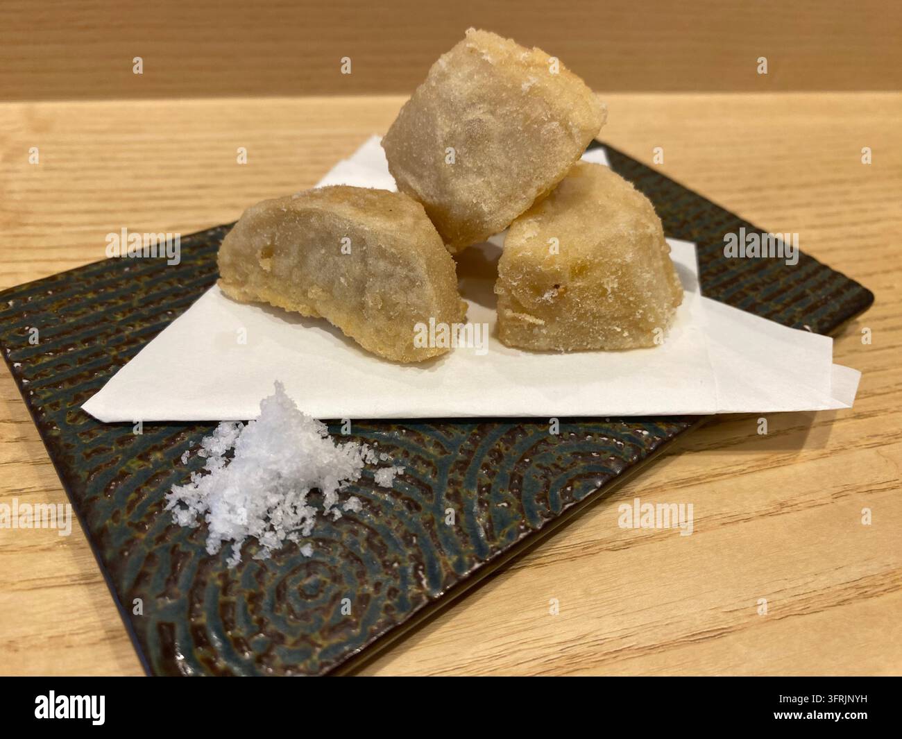 Nahaufnahme von knusprig gebratener Taro-Wurzel (satoimo no karaage), serviert mit Salz in einem japanischen Restaurant in Fukuoka, Japan. - Smartphone-aufgenommenes Stockfoto