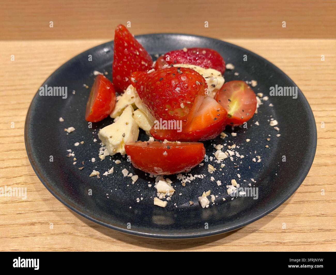Nahaufnahme von frischen Erdbeeren, Tomaten und cremigem seltenem Käsekuchen, serviert in einem japanischen Restaurant in Fukuoka, Japan. - Smartphone-aufgenommenes Stockfoto