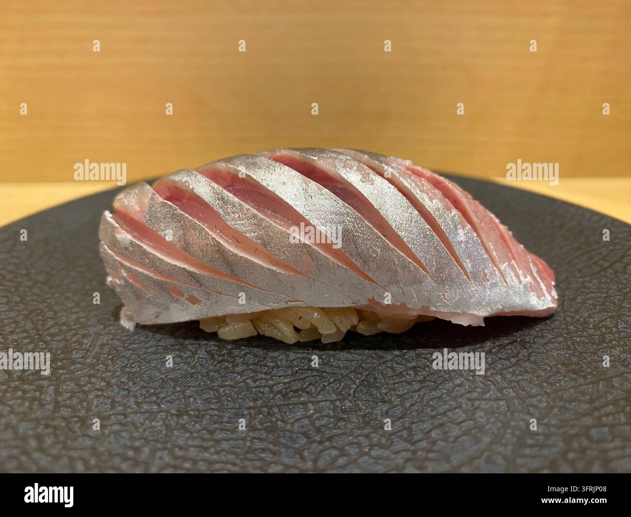 Horsemackerel-Nigiri-Sushi mit dekorativen Messerschnitten auf dem Fisch, ohne zusätzliche Beläge, in einem Sushi-Restaurant in Hakata, Fukuoka, Japan. - Smartphone-aufgenommenes Stockfoto