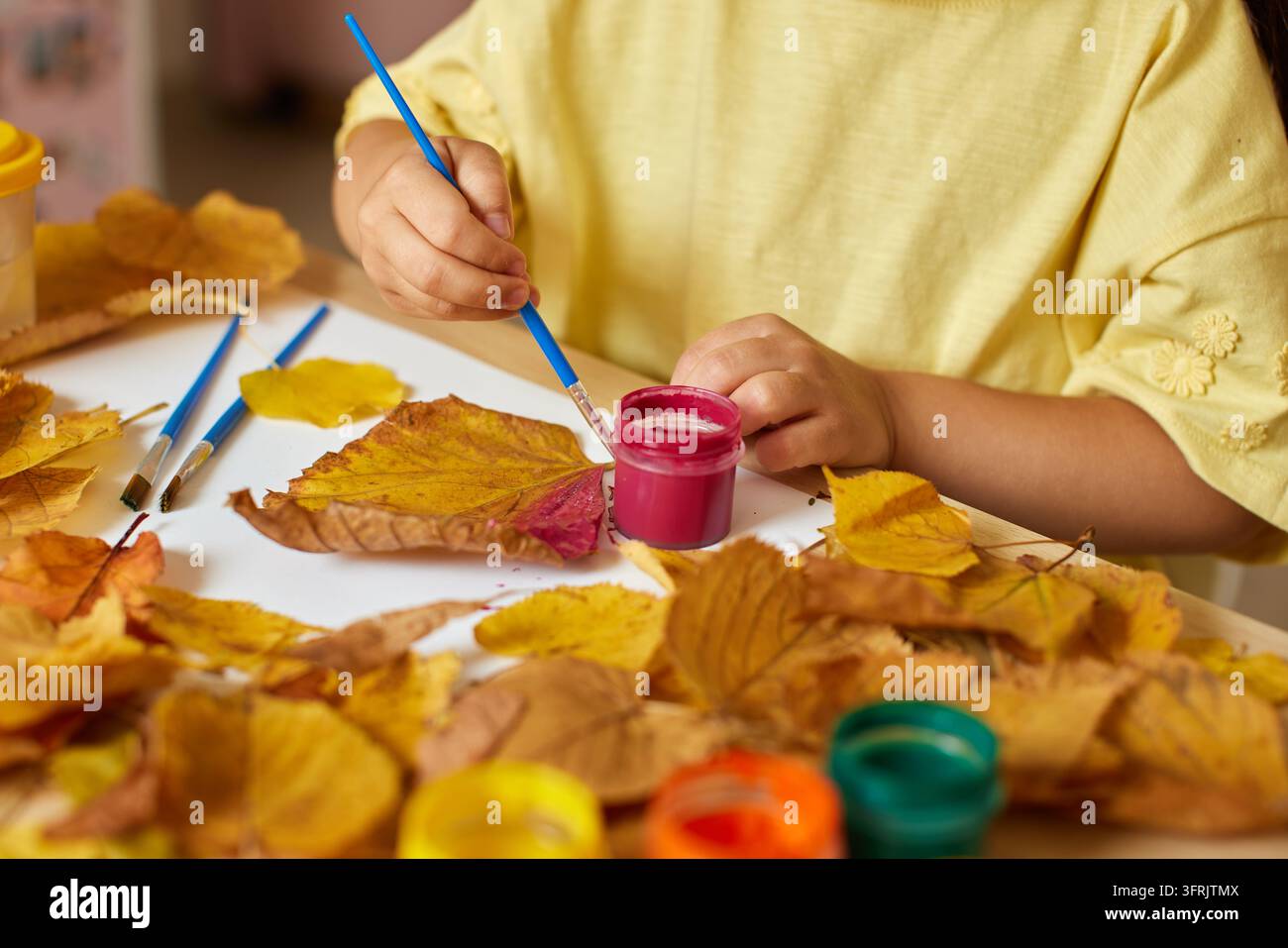 Kind malt Herbstblätter für eine kreative Bastelaktivität Stockfoto