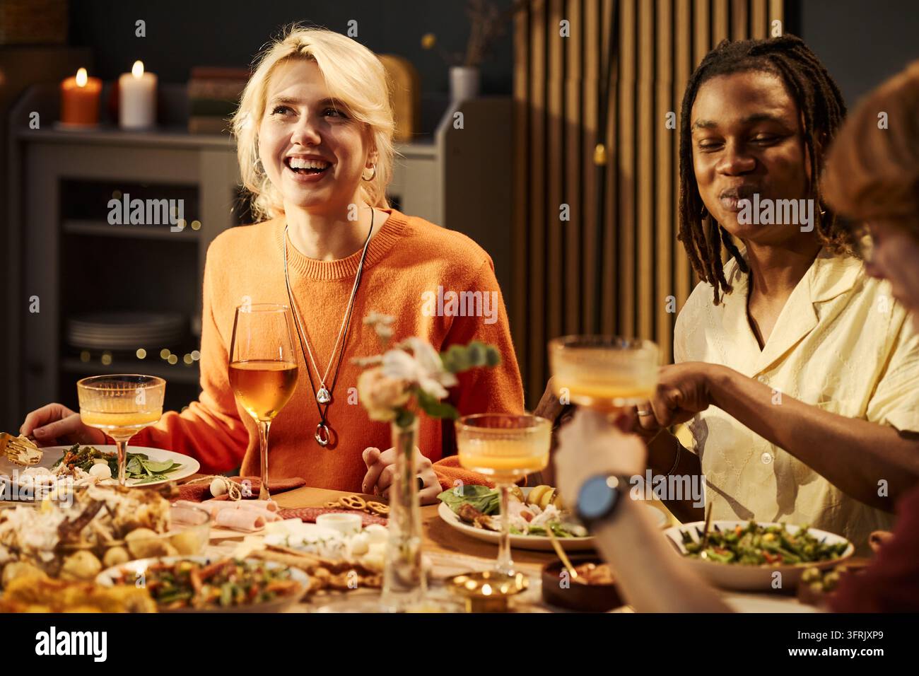 Fröhliche verschiedene Freunde feiern ein festliches Abendessen zu Hause Stockfoto