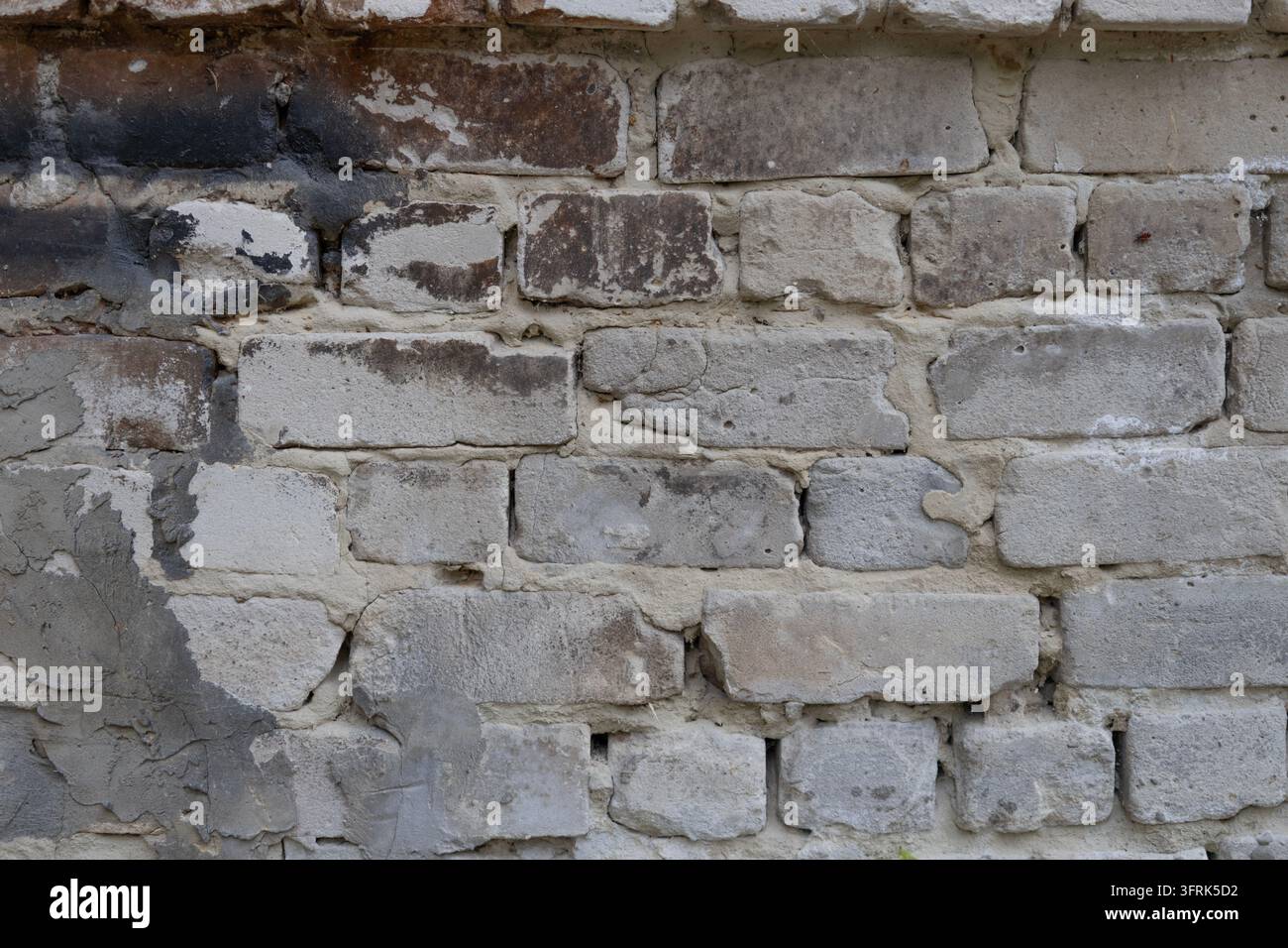 Alte verwitterte weiße Ziegelwand-Texturhintergrund mit grobem Mörtel, Rußspuren und beschädigten Oberflächendetails. Vintage-Maurstein-Struktur-Hintergrund Stockfoto