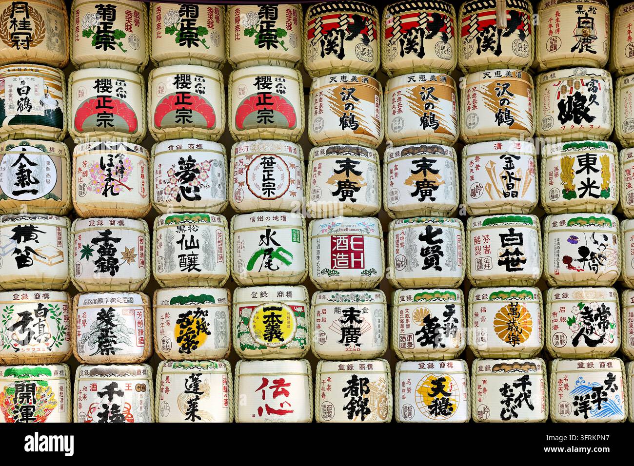Reihen strohumwickelter Fässer, die mit Kalligrafie und Brauereisymbolen bemalt sind, traditionell von japanischen Sake-Herstellern Shinto-Schreinen angeboten Stockfoto