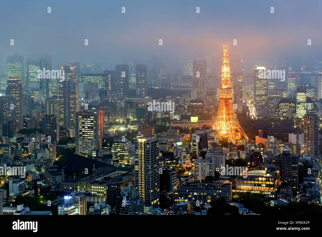 Erhöhte Ansicht des orange beleuchteten Kommunikationsturms über Hochhausbüros und Wohnungen im Zentrum von Tokio an einem dunstigen Frühlingsabend Stockfoto