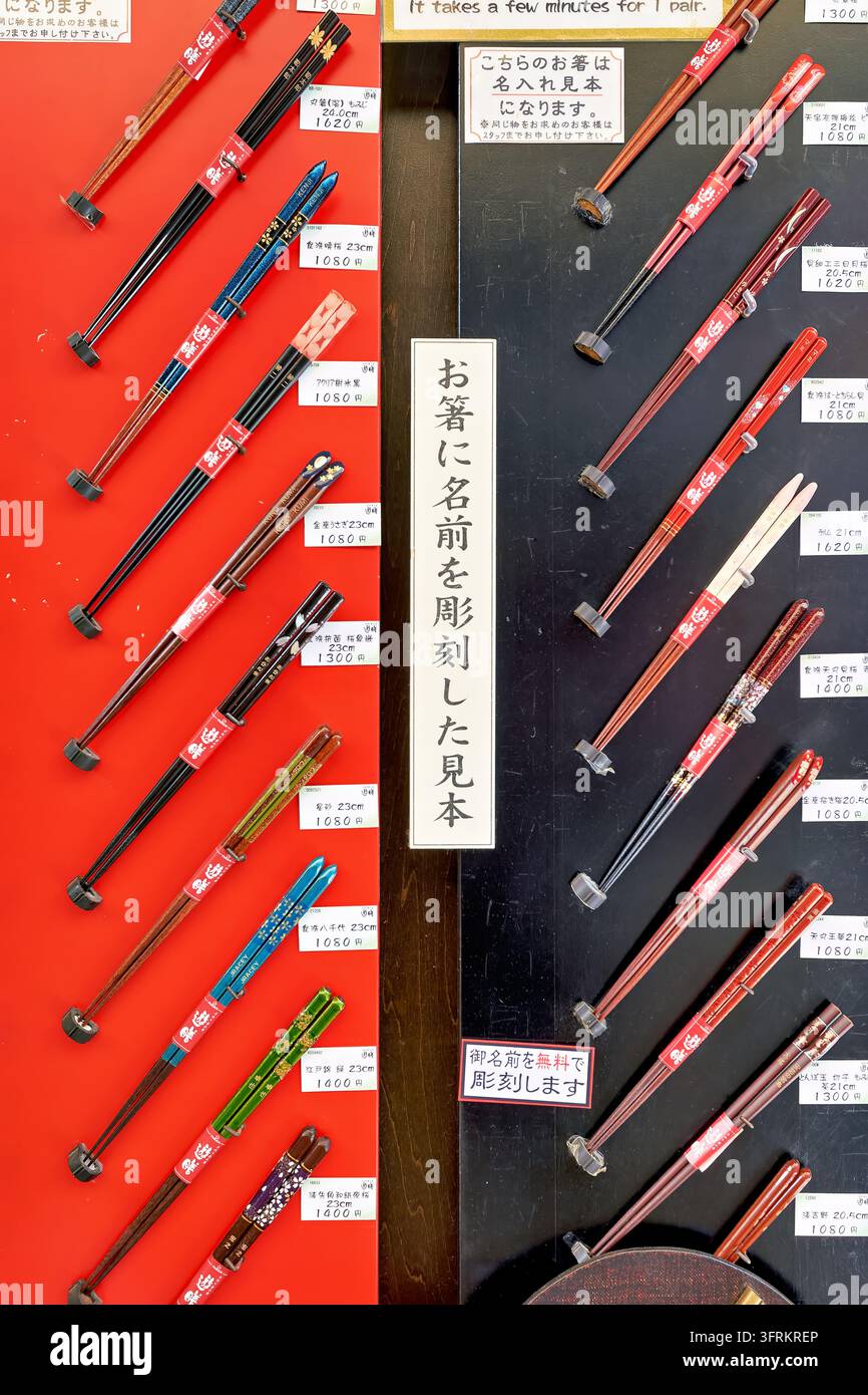 Personalisierte Essstäbchen-Proben mit kostenloser Namensgravur, in Yen auf roten und schwarzen Displaytafeln in einem japanischen Souvenirladen. Stockfoto
